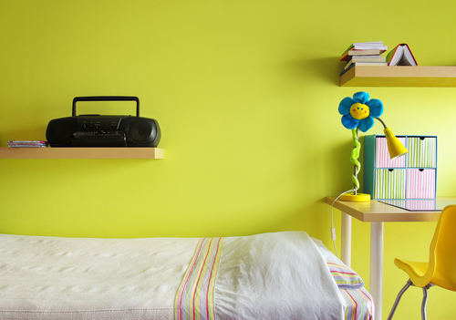 Detail of a teenager bedroom with desk, bed, shelf, and yellow wall